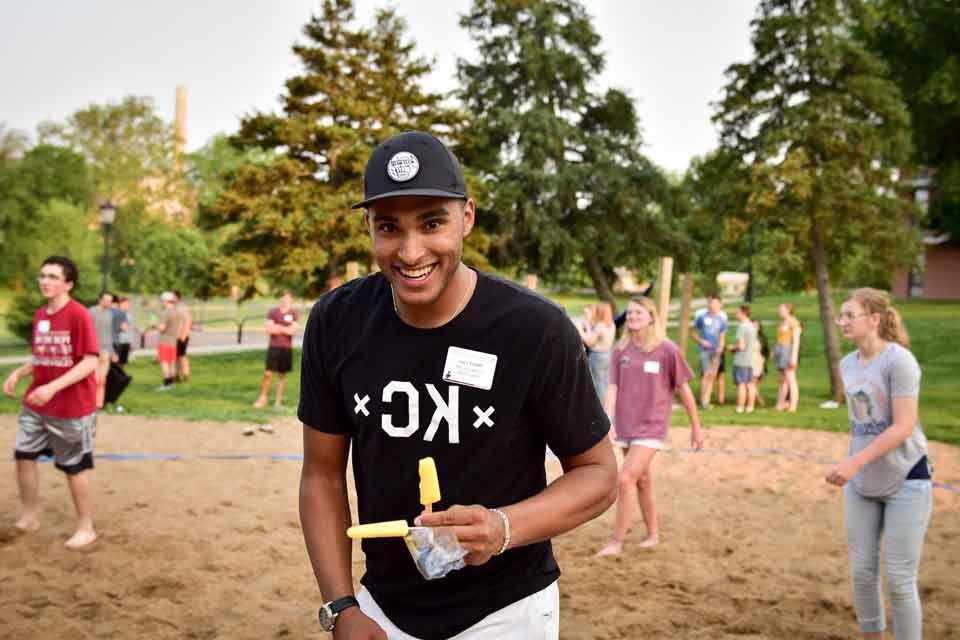 A student grins during a sand volleyball game